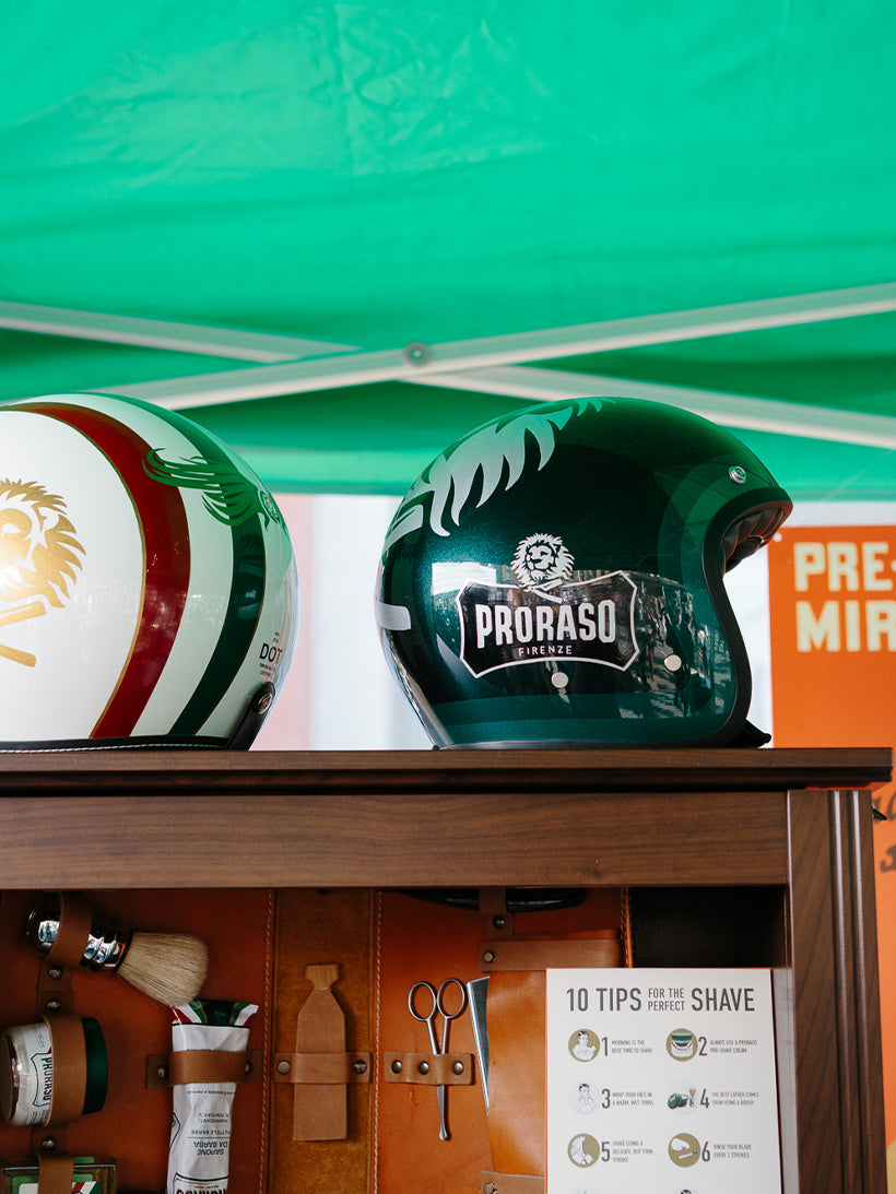 Image of the Proraso booth at the Distinguished Gentleman's Ride- two motorcycle helmets on top of a bookcase with Proraso product on the shelves
