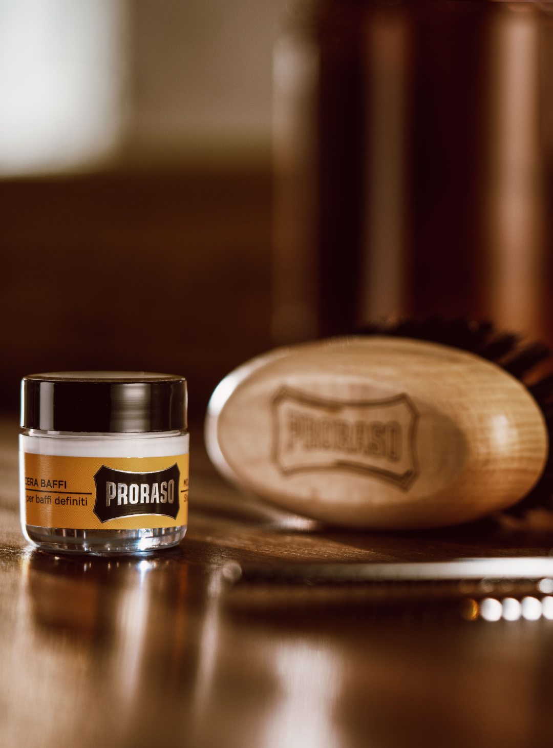 Proraso Moustache Wax and Moustache Brush sitting on a brown barber counter
