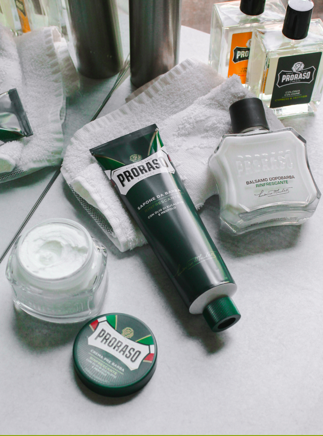 Refresh Formula Pre-Shave Cream jar open, Shave Cream Tube, After Shave Balm and two bottles of cologne sitting on the bathroom counter