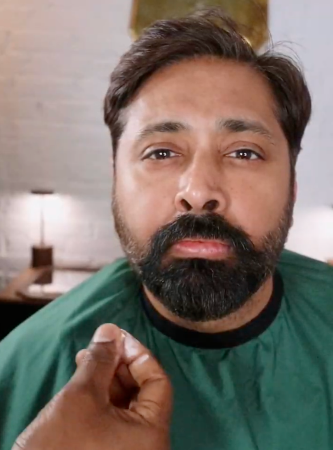 Man with beard getting Moustache Wax applied and heard styled in a barber chair