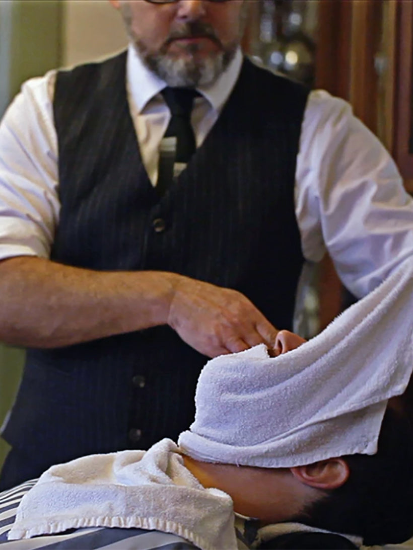 Barber holding towel over man's face