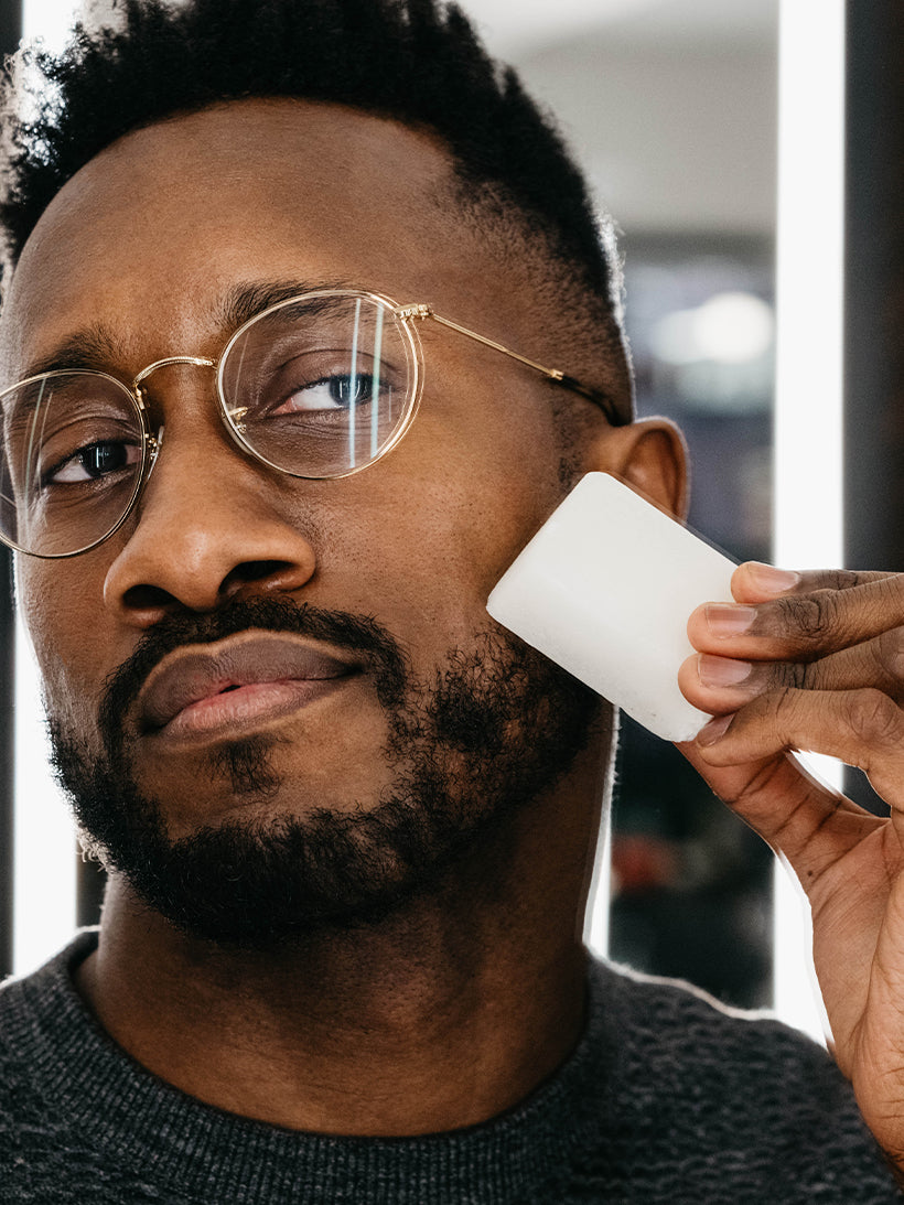 Image of man holding the Post-Shave Stone to his cheek to help seal up any nicks or cuts 