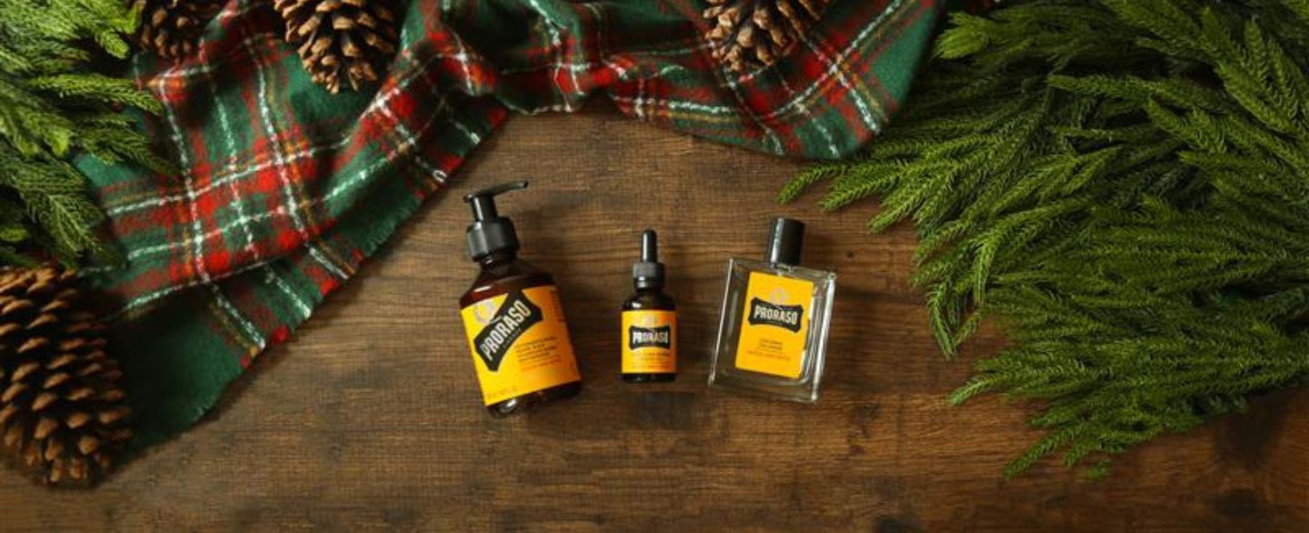 Wood & Spice Beard Wash, Beard Oil and Cologne on a wooden floor surrounded by a plaid blanket and tree foliage 