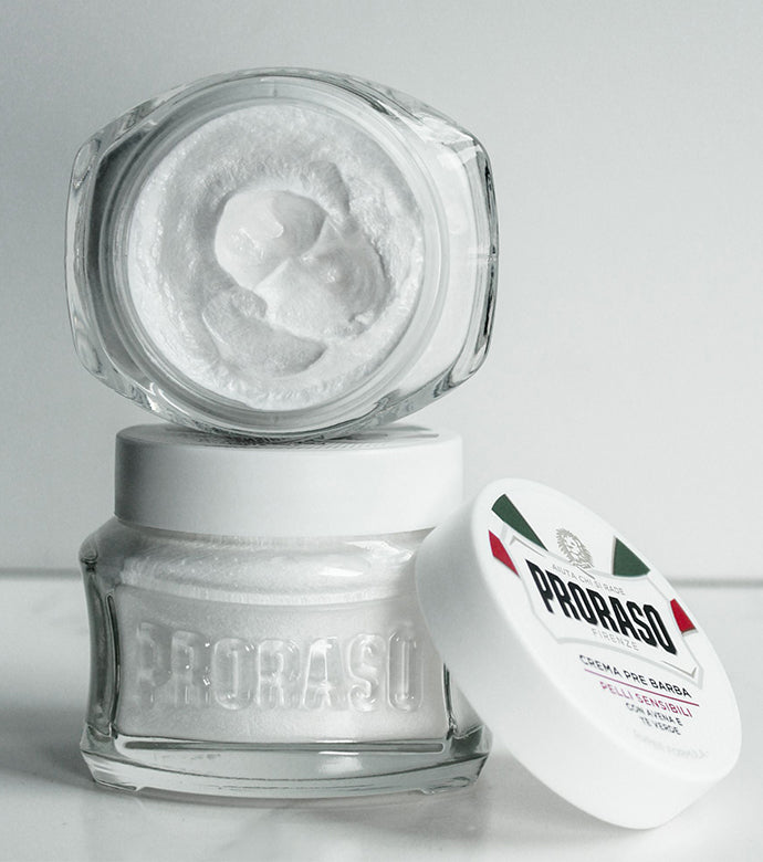 One jar of Sensitive Pre-Shave Cream closed with an open, front facing jar of Sensitive Pre-Shave Cream with lid balanced on bottom jar on white background