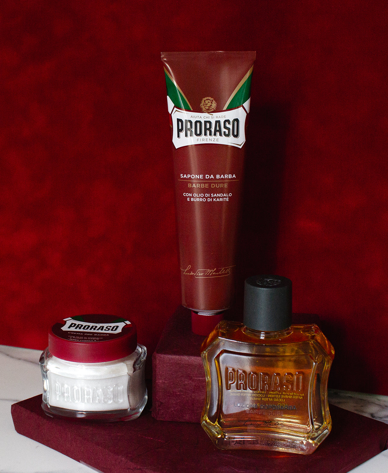 Coarse Beard Formula three step lineup from left to right Pre-Shave Cream, Shave Cream Tube and After Shave Lotion sitting on graduated red steps with a red background