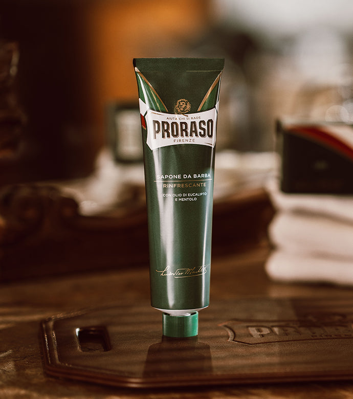 Refreshing Shave Cream Tube sitting on dark brown table with white Proraso towels and packaging sitting in background 