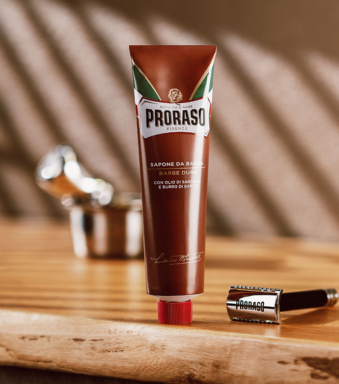 Coarse Beard Shave Cream Tube sitting on light wood table with Proraso safety razor next to it and Professional Shave Brush in a silver bowl in the background