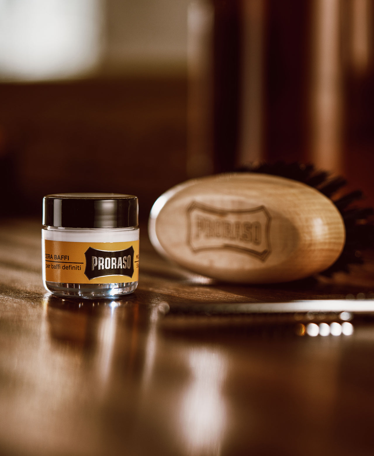 Wood & Spice Moustache Wax jar sitting on dark brown barber table with a Moustache and Beard Brush sitting in the backgournd