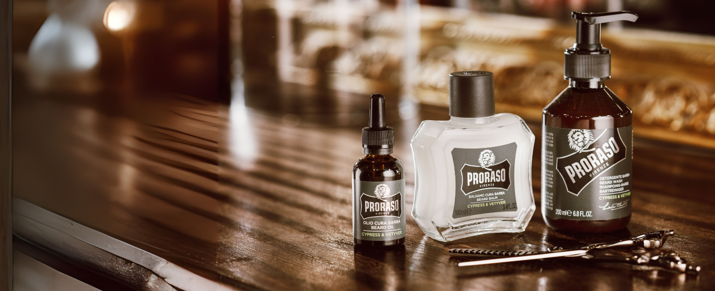 Cypress & Vetyver Beard Oil, Beard Balm and Beard Wash sitting on a brown wood barber counter with a pair of scissors in front 