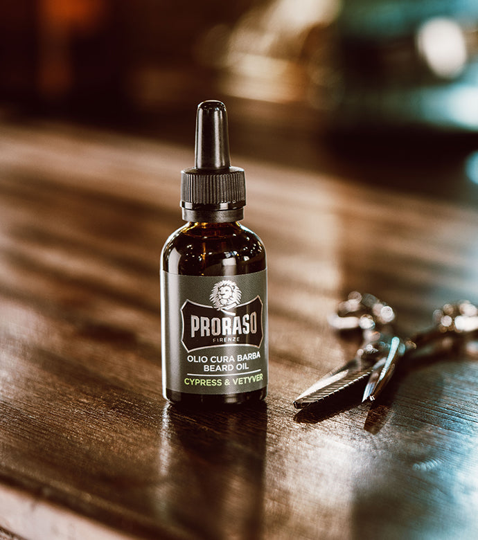 Cypress & Vetyver Bottle of Beard Oil sitting on dark wood counter with a pair of barber scissors sitting next to it