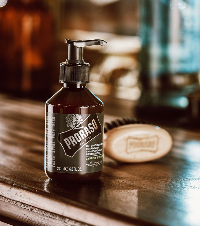 Cypress & Vetyver Beard Wash sitting on wooden table with Moustache and Beard Brush sitting behind