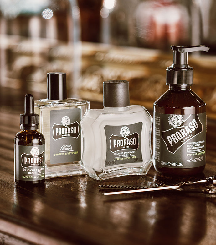 Full Cypress & Vetyver Beard collection from left to right Beard Oil, Cologne, Beard Balm and Beard Wash with scissors in front on a dark wooden table