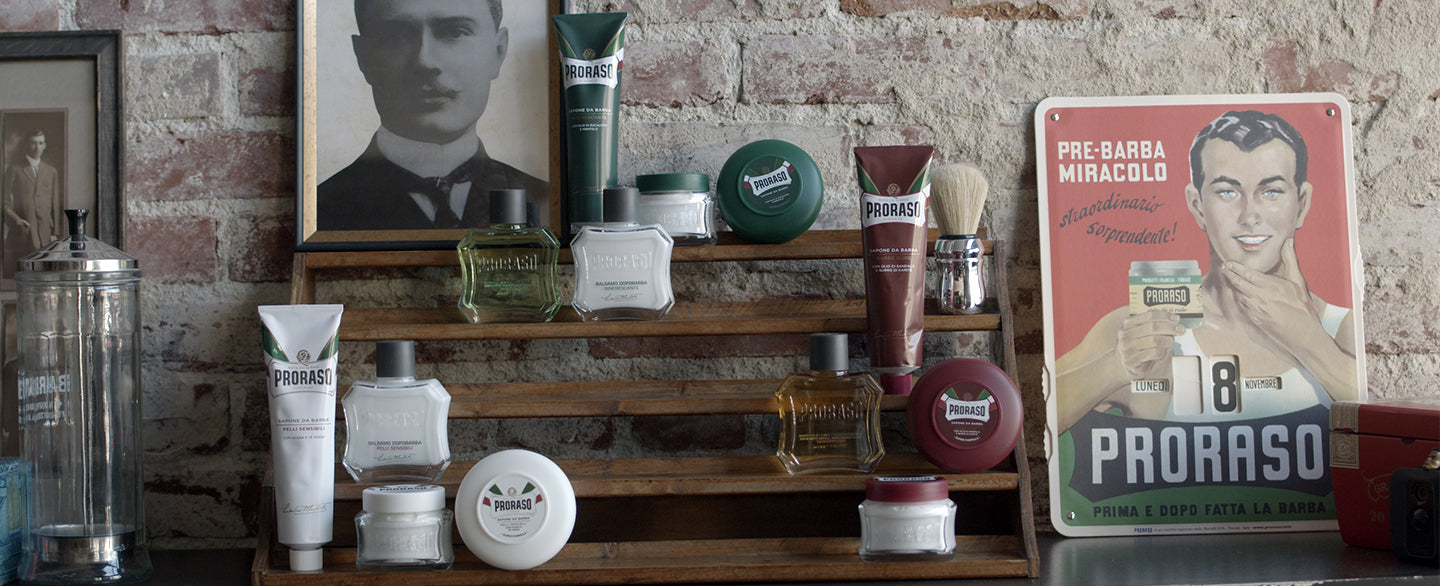 From left to right Proraso Sensitive Formula, Refreshing Formula and Nourishing formula sitting on a graduated shelf with historical Proraso posters in the background