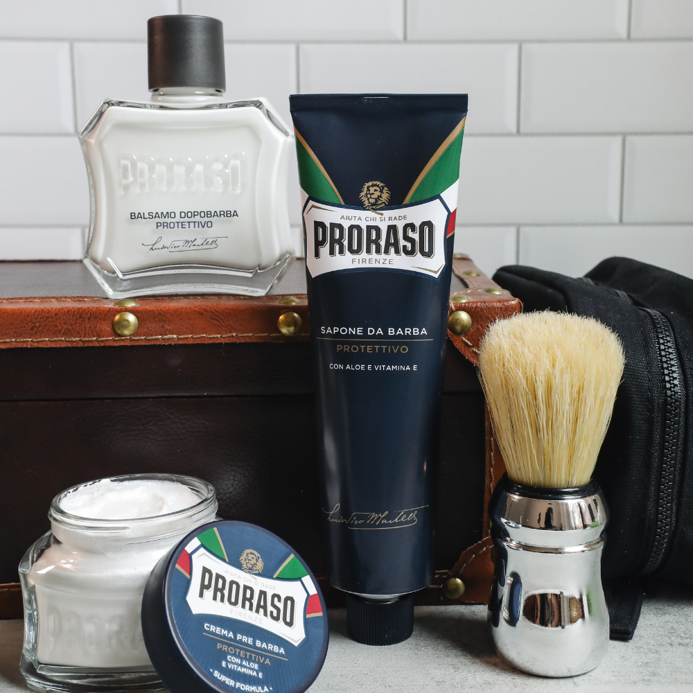 Full ProraProtective lineup in front of a white tile background. Including Protective Pre-Shave Cream, Shave Cream Tube, After Shave Balm, and Professional Shaving Brush