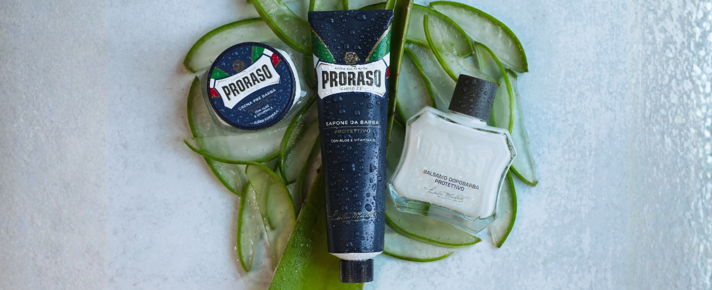 Protective Formula Pre-Shave Cream, Shave Cream and After Shave Balm sitting on a bed of Aloe Vera on a grey table