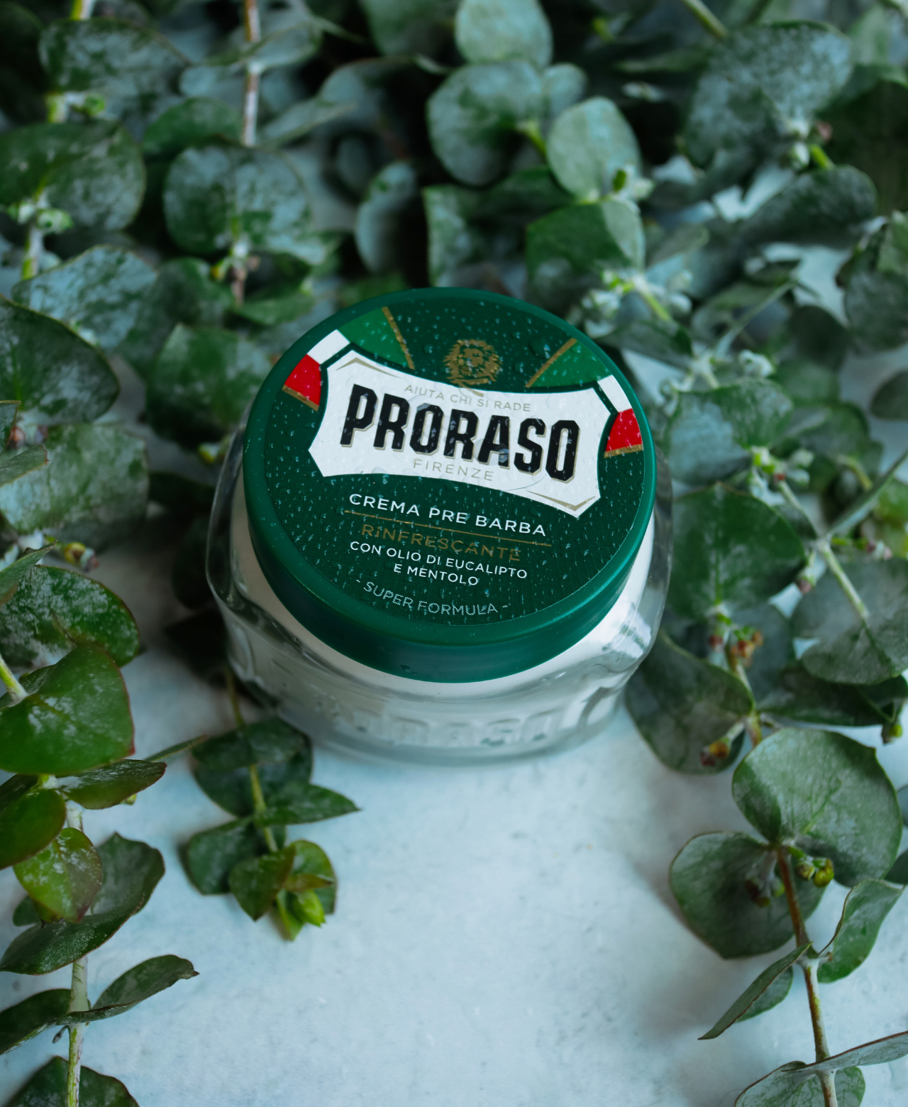 Refreshing Pre-Shave Cream jar sitting on a grey table with Eucalyptus leaves in the background