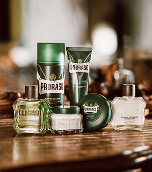 Refreshing Shave Formula lineup from left to right: After Shave Balm, Shave Foam, Pre-Shave Cream, Shave Cream Tube and After Shave Balm sitting on a dark brown table