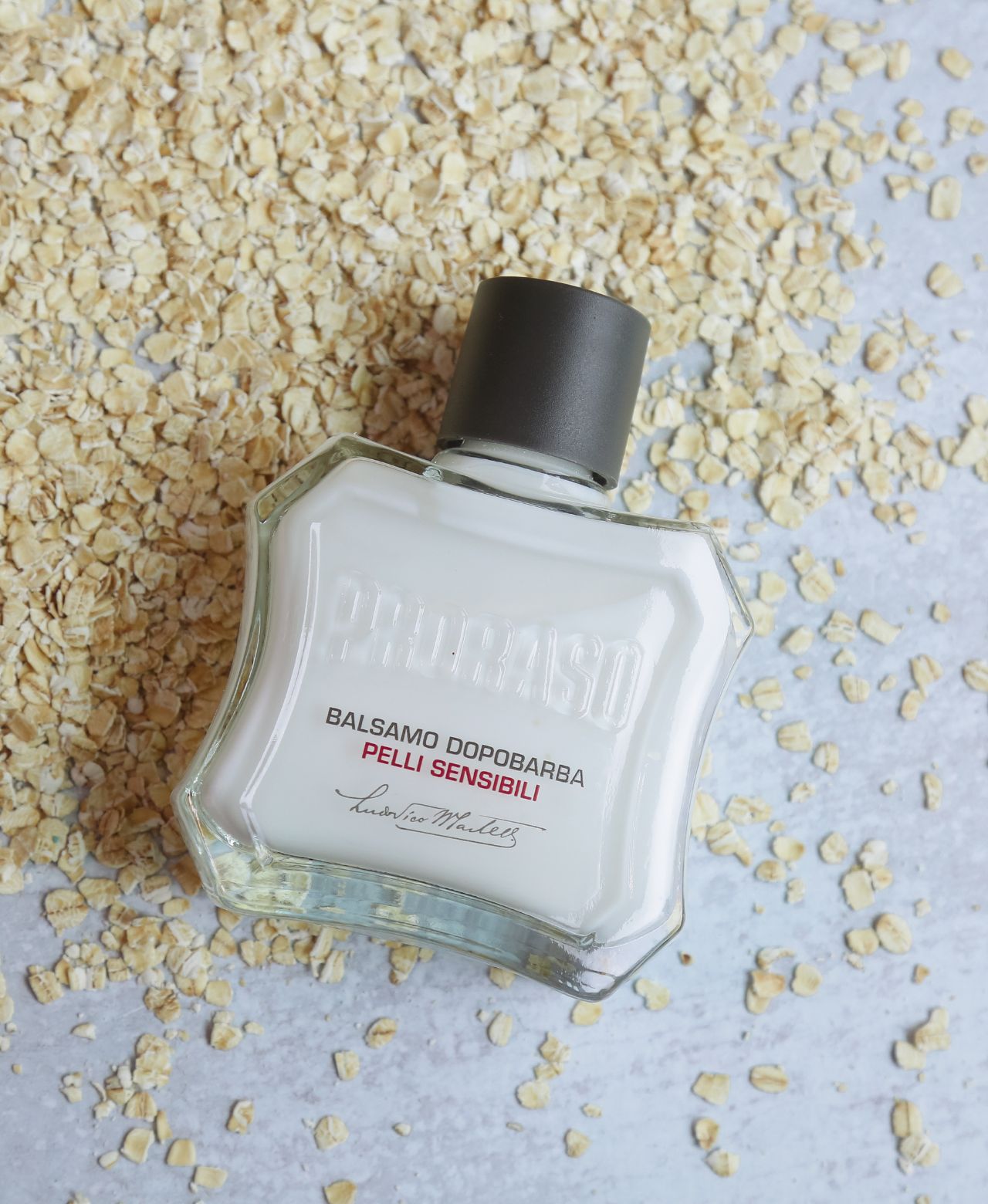 Sensitive After Shave Balm sitting on top of oatmeal on a grey table