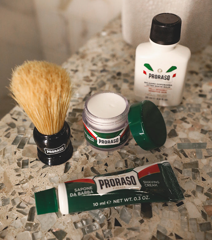 Four piece Travel Shave Kit on bathroom counter including mini Refreshing Pre-Shave Cream, Refreshing Shave Cream Tube, After Shave Lotion and mini Shave Brush
