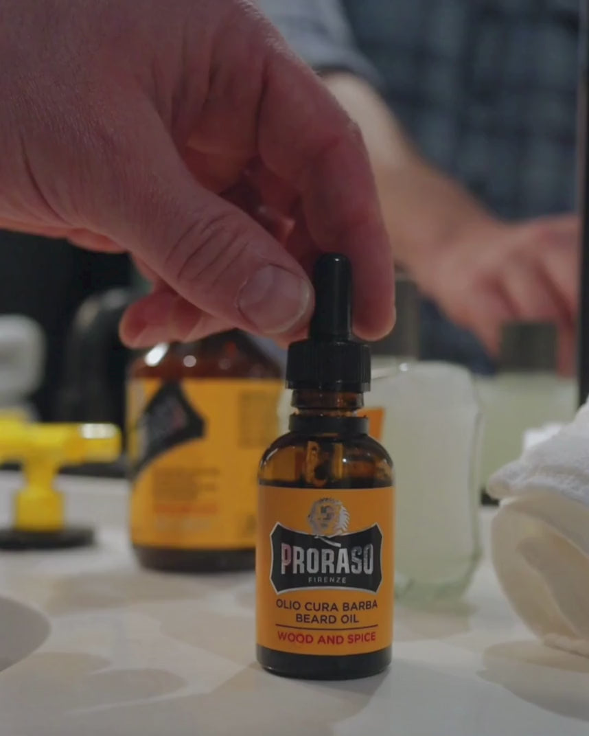 Man applying Beard Oil in Wood & Spice Fragrance to his thick, full beard in a bathroom