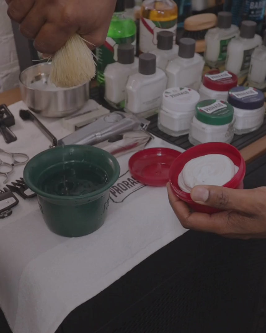Man building a lather with Shave Soap in a bowl for Coarse Beards and a Professional Shave Brush at a barbershop counter