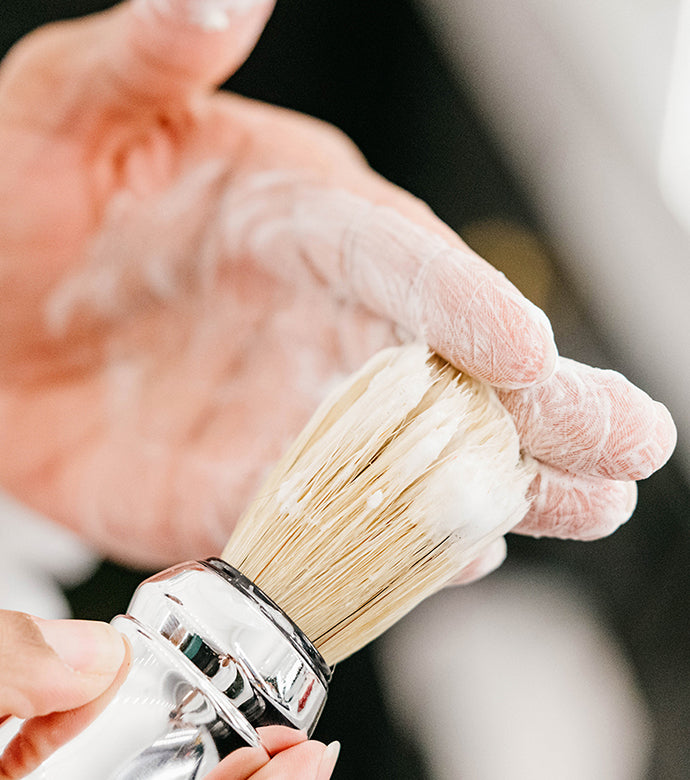 Proraso Professional Shaving Brush being used to make a lather with hands, touching fingers covered in a thick lather.