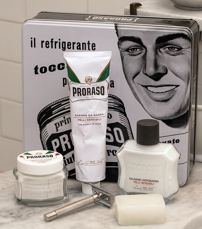 Proraso Vintage Toccasana Tin: Sensitive Skin on bathroom counter including Proraso Sensitive Pre-Shave Cream, Proraso Sensitive Shaving Cream Tube, Proraso After Shave Balm, collectable tin, Proraso Post-Shave Stone and safety razor.