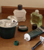 Counter set up including Proraso Refreshing Shave Cream Tube, Proraso Refreshing After Shave Lotion, Proraso Refreshing After Shave Balm and a shaving mug with a thick lather with a Proraso Professional Shaving Brush.