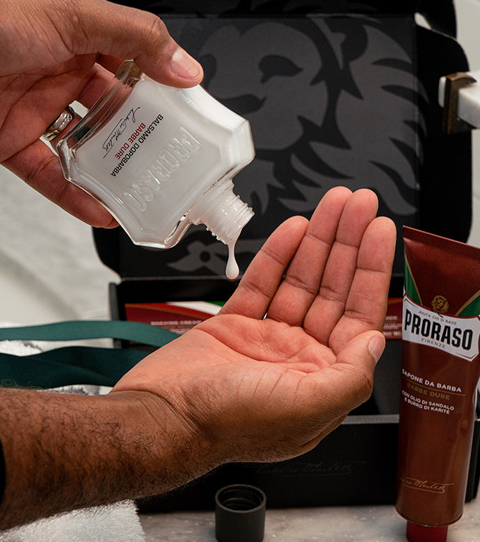 Proraso Nourishing for Coarse Beards being poured into palm of hand after a clean shave.  Proraso Nourishing for Coarse Beards Shaving Cream Tube sitting on bathroom counter.