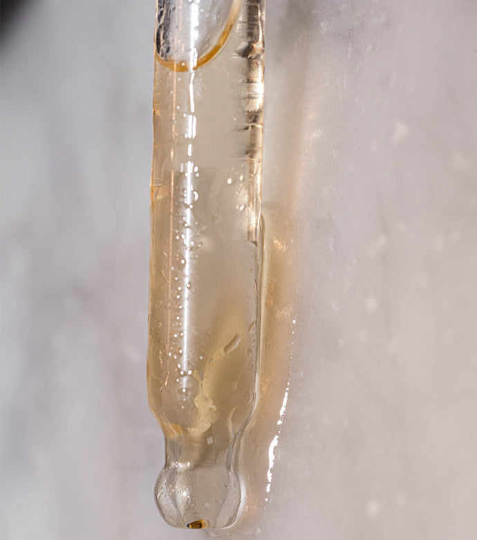 Closeup of Beard Oil in Beard Oil in dropper sitting on a white marble counter