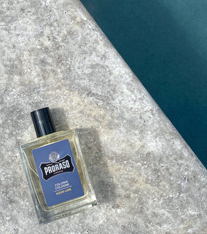 Proraso Azur Lime Cologne sitting on the edge of a swimming pool.