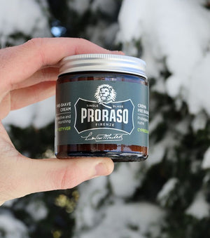 Proraso Single Blade Pre-Shave Cream being held in hand in front of snow covered Cedar Tree.