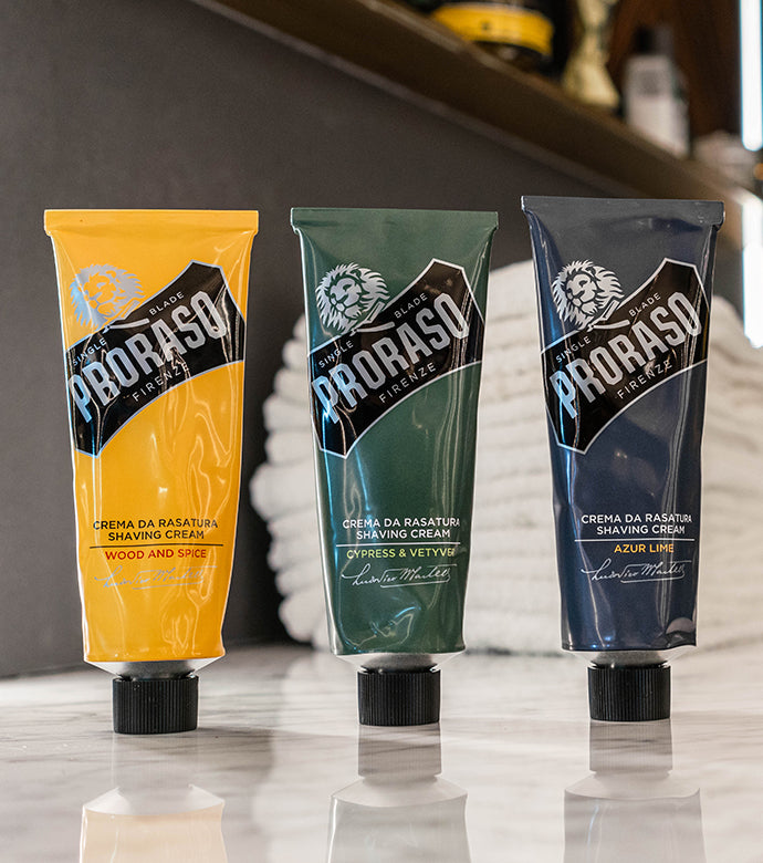 Proraso Single Blade Shave Cream in a Tube in all three fragrances: Wood and Spice, Cypress & Vetyver and Azur Lime sitting on the counter of a barber shop.